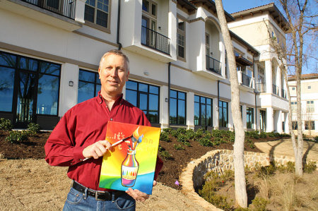 Glenn Olson, the owner of the Lakeside Bottle and Bottega, with a paint brush and canvas in front of his location in The Shops at Lakeside.